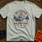 Fifty State Backyard - T-Shirt in Bay - A circular badge design featuring an off-road SUV parked next to a winding road,...