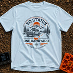 Fifty State Backyard - T-Shirt in Chambray - A circular badge design featuring an off-road SUV parked next to a winding...