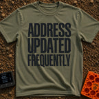 Location Not Found - T-Shirt in Moss - A text-only design featuring the phrase "ADDRESS UPDATED FREQUENTLY" stacked in...