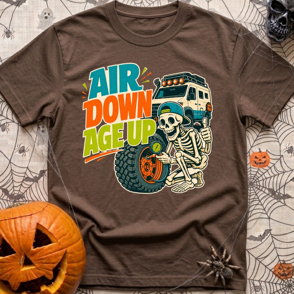 Aired Down Aged Up - T-Shirt in Espresso - A cartoon skeleton wearing a backwards baseball cap gives a thumbs-up while...
