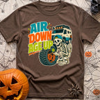 Aired Down Aged Up - T-Shirt in Espresso - A cartoon skeleton wearing a backwards baseball cap gives a thumbs-up while...