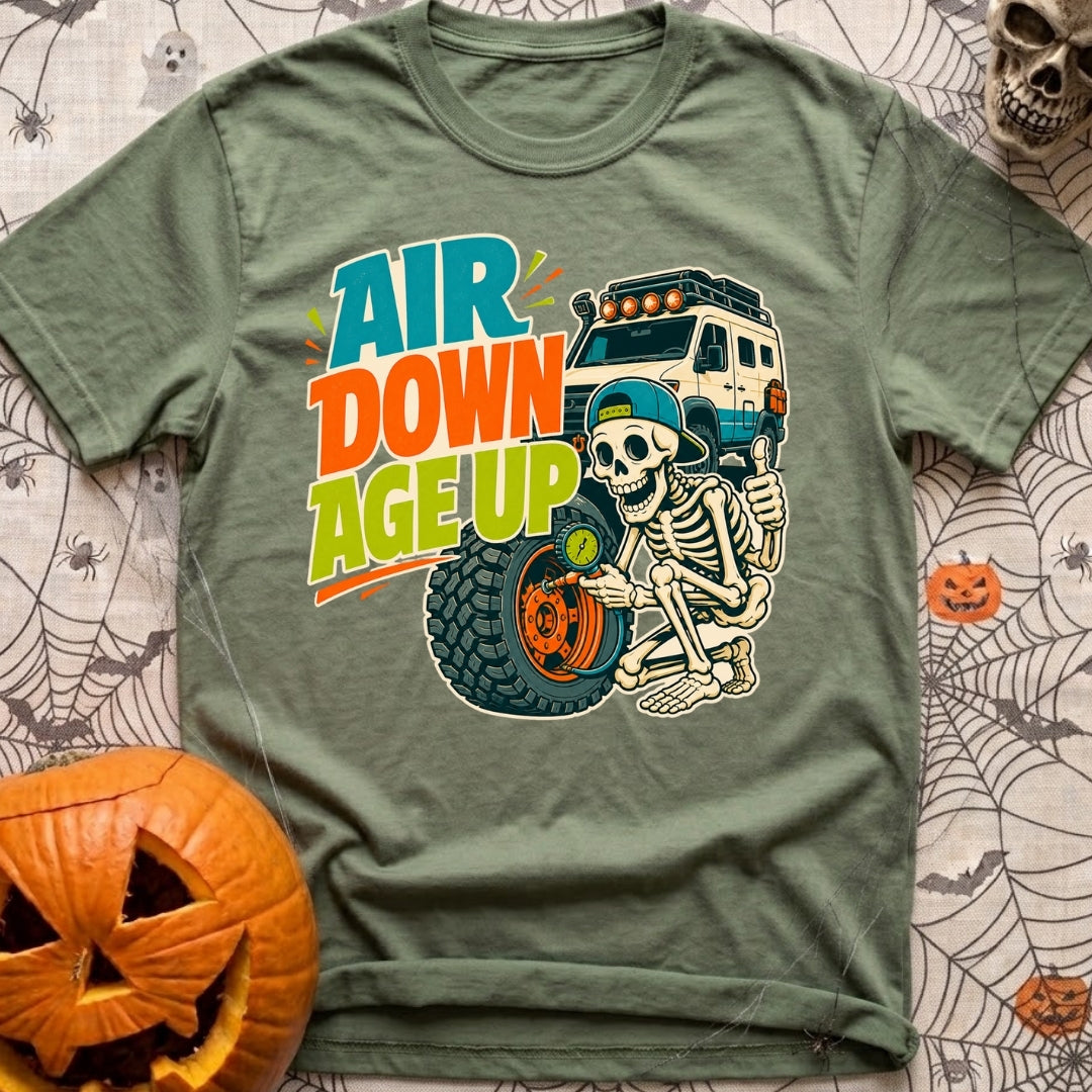 Aired Down Aged Up - T-Shirt in Moss - A cartoon skeleton wearing a backwards baseball cap gives a thumbs-up while using...