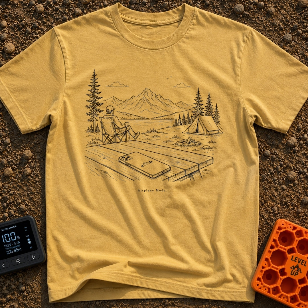 The Real Airplane Mode - T-Shirt in Mustard - A black and white line drawing of a smartphone resting on a wooden picnic...
