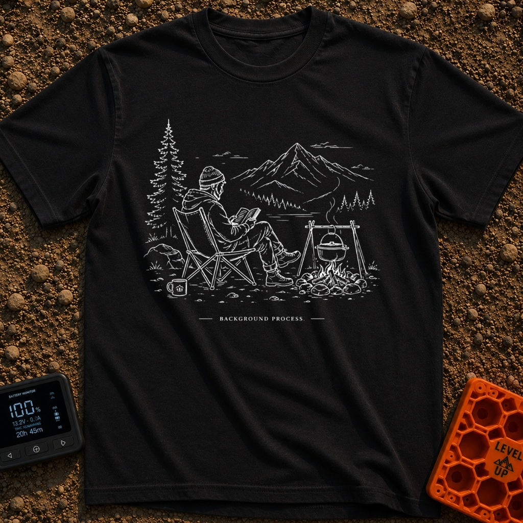Running In The Background - T-Shirt in Black - A line-art illustration of a man wearing a beanie sitting in a camp chair...