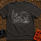 Running In The Background - T-Shirt in Graphite - A line-art illustration of a man wearing a beanie sitting in a camp...