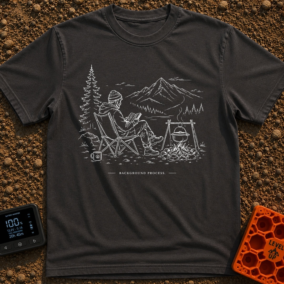 Running In The Background - T-Shirt in Graphite - A line-art illustration of a man wearing a beanie sitting in a camp...