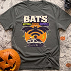 Bat Signal Boosters - T-Shirt in Pepper - A cartoon bat forms the shape of a Wi-Fi symbol over a camper van with a...