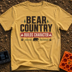 Character In Bearland - T-Shirt in Mustard - A vintage-style typographic design featuring the text "BEAR COUNTRY BUILDS...