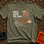 Boots Know Best - T-Shirt in Moss - A pair of decorated brown western boots standing next to a steaming camp mug, with...