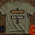 Breakfast Next Dirt Road - T-Shirt in Moss - A graphic of a wooden directional signpost with two arrows; the top arrow...