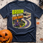Brooms Turn Better - T-Shirt in Navy - A cartoon illustration showing a witch flying effortlessly in a tight circle...