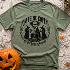 Wake The Coven - T-Shirt in Moss - A black and white circular illustration of three witches standing around a cauldron...