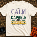 Calm Capable Camped Out - T-Shirt in Ivory - A typographic design featuring the words "CALM CAPABLE CAMPED OUT" arranged...