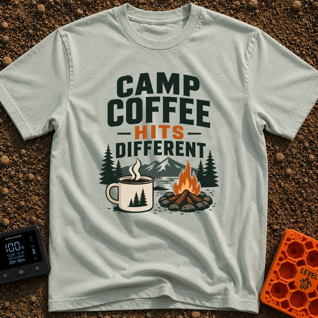 Brew Hits Different - T-Shirt in Bay - A graphic showing a steaming enamel camp mug next to a stone-ringed campfire, set...