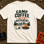 Brew Hits Different - T-Shirt in Ivory - A graphic showing a steaming enamel camp mug next to a stone-ringed campfire,...