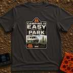 Easy Until You Park - T-Shirt in Graphite - A badge-style illustration showing a white campervan parked on uneven ground...