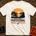 Professional Sunset Watcher - T-Shirt in Ivory - An illustration of a person sitting in a camp chair on a rocky overlook,...