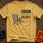 Chair Called Dibs - T-Shirt in Mustard - A green folding camp chair with a mug in its cup holder and a towel draped over...