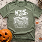 Dew Or Die - T-Shirt in Moss - A white line drawing from the perspective of a vehicle's front seat, showing a hand wiping...