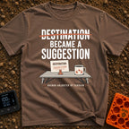 Destinations Are Suggestions - T-Shirt in Espresso - A folding camp table holds a coffee mug with a mountain graphic and...