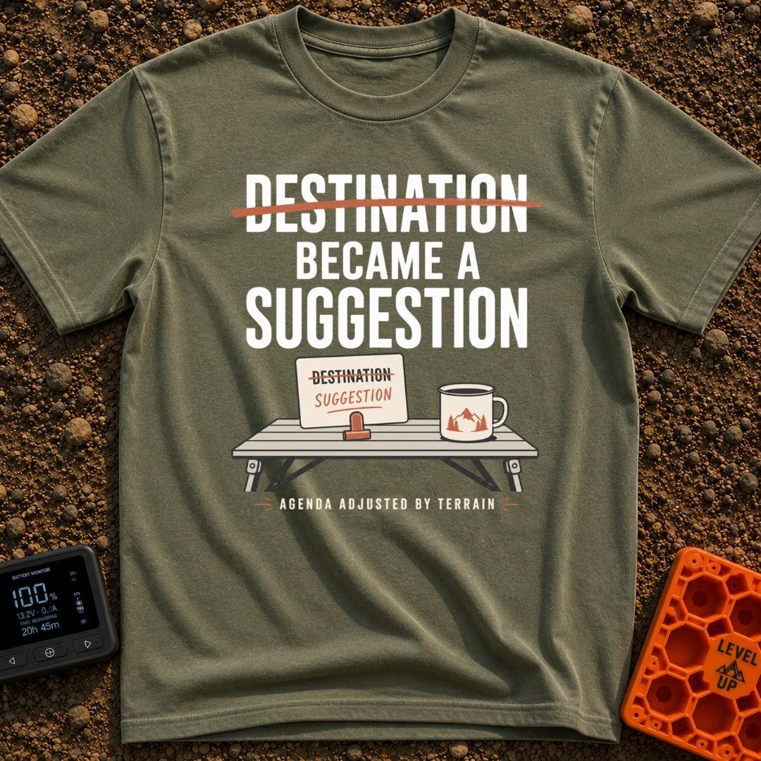 Destinations Are Suggestions - T-Shirt in Moss - A folding camp table holds a coffee mug with a mountain graphic and a...