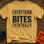 Eventually, It Bites - T-Shirt in Mustard - A text-only design reading "EVERYTHING BITES EVENTUALLY" in bold black,...