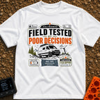 Tested By Poor Decisions - T-Shirt in White - The design features a camper van parked on rocky terrain with mountains and...