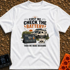 First Check The Battery - T-Shirt in White - A white camper van with a roof-mounted solar panel parked near mountains and...