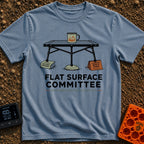 Flat Surface Club - T-Shirt in Blue Jean - A drawing of a foldable camp table with a green enamel mug on top, whose legs...