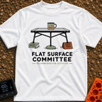 Flat Surface Club - T-Shirt in White - A drawing of a foldable camp table with a green enamel mug on top, whose legs are...