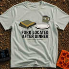 Fork Found Too Late - T-Shirt in Bay - A cartoon illustration showing a fork partially hidden under a folded green...