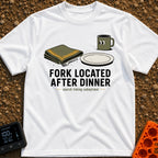 Fork Found Too Late - T-Shirt in White - A cartoon illustration showing a fork partially hidden under a folded green...