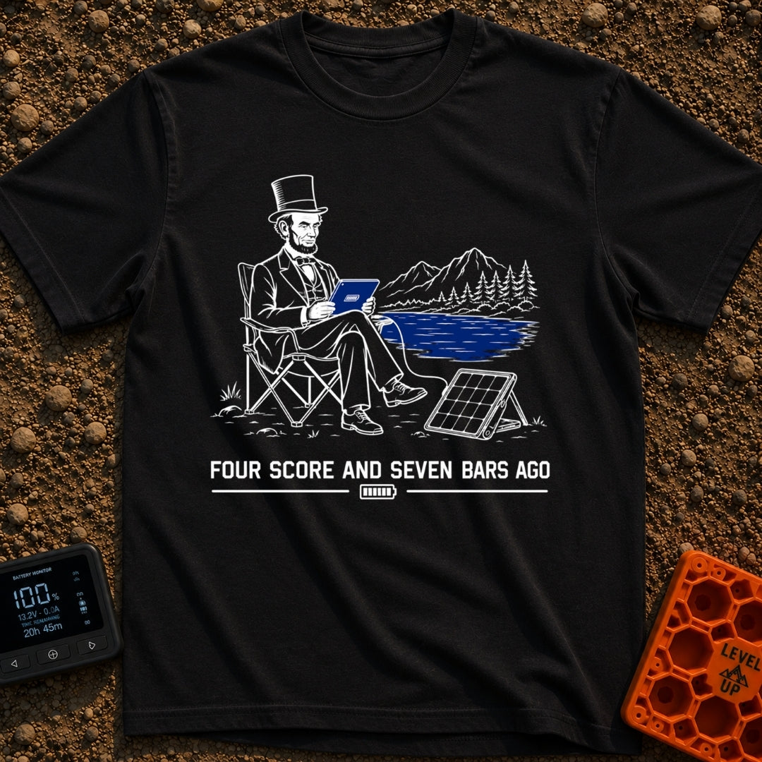 Lincoln Unplugged Adventure - T-Shirt in Black - A line drawing of Abraham Lincoln sitting in a folding camp chair by a...