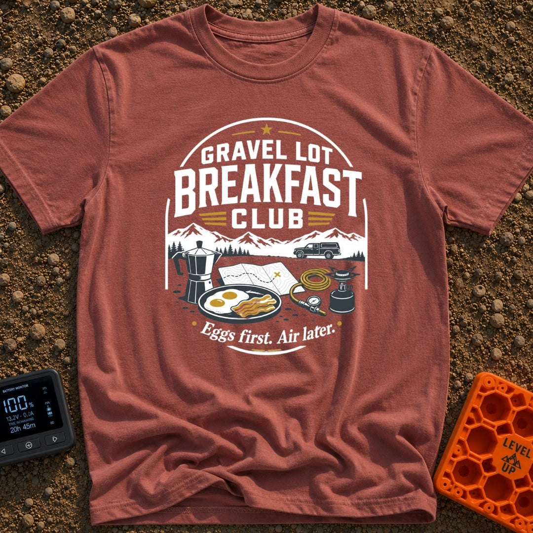 Gravel Gourmet Gathering - T-Shirt in Brick - A camping breakfast setup featuring a Moka pot, a pan of eggs and bacon, a...