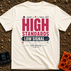 Standards And Signals - T-Shirt in Ivory - A typographic design reading "HIGH STANDARDS LOW SIGNAL" and "Still thriving",...