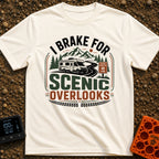 I Brake For Overlooks - T-Shirt in Ivory - A Class C motorhome drives along a winding paved road next to a brown 'Scenic...