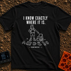 I Know It's Here - T-Shirt in Black - A white line drawing of a person in a cap and shorts pointing at an open backpack,...