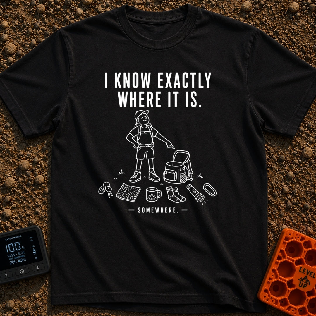 I Know It's Here - T-Shirt in Black - A white line drawing of a person in a cap and shorts pointing at an open backpack,...