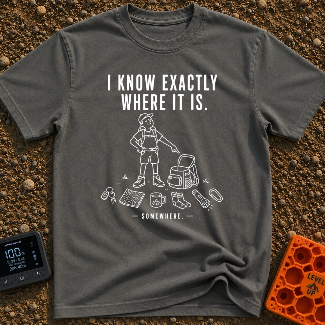 I Know It's Here - T-Shirt in Pepper - A white line drawing of a person in a cap and shorts pointing at an open backpack,...