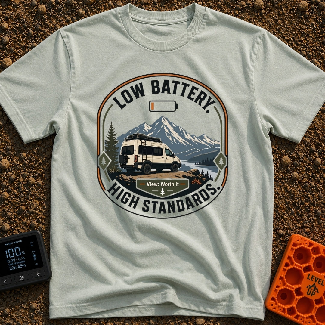 Low Battery High Standards - T-Shirt in Bay - A badge-style graphic featuring a white camper van parked on a dirt...