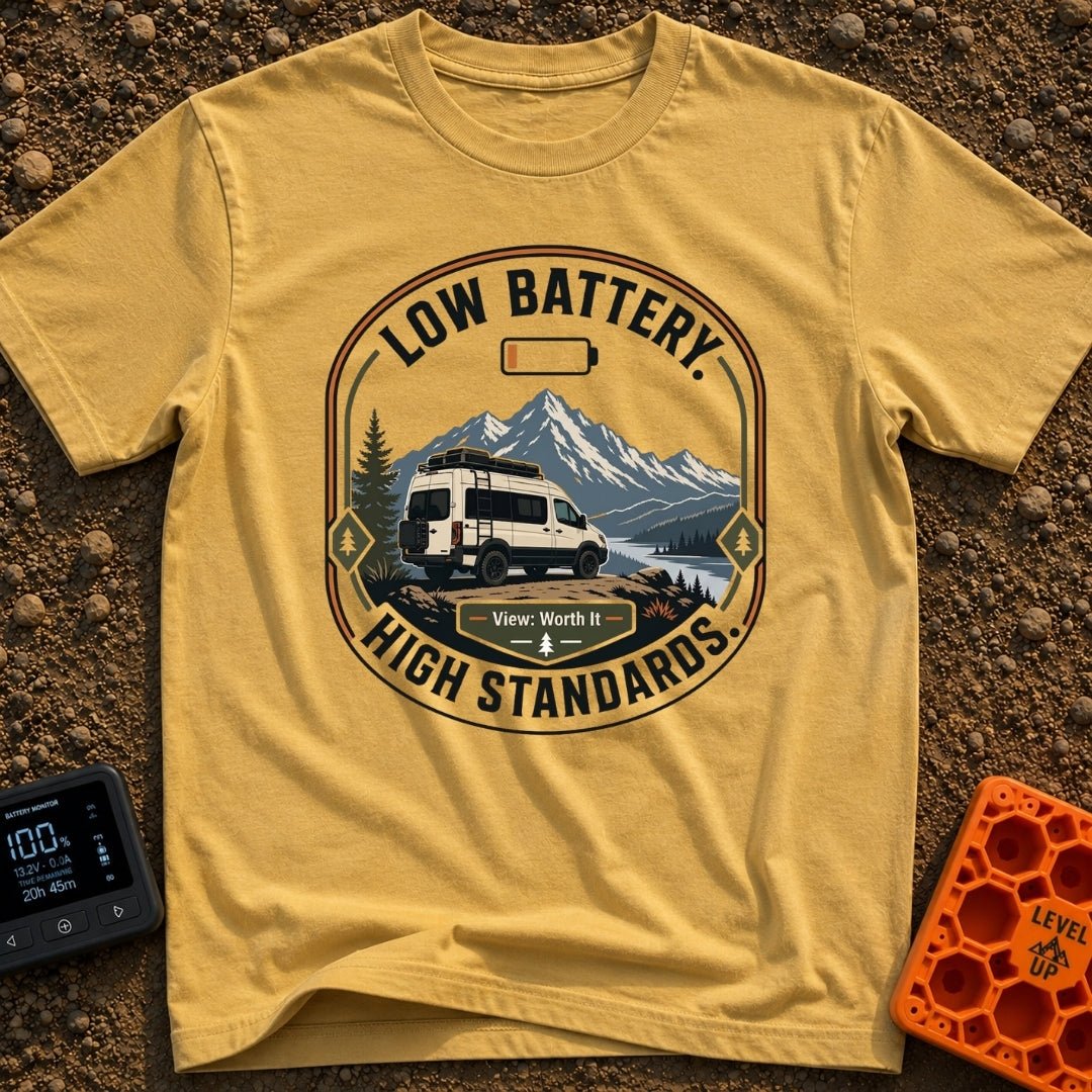Low Battery High Standards - T-Shirt in Mustard - A badge-style graphic featuring a white camper van parked on a dirt...
