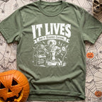 The Mad Roaster - T-Shirt in Moss - A white line drawing of a mad scientist using jumper cables attached to a 12-volt...