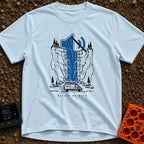 Stream On Mute - T-Shirt in Chambray - An illustration of a camper van parked at the base of a steep cliff with pine...