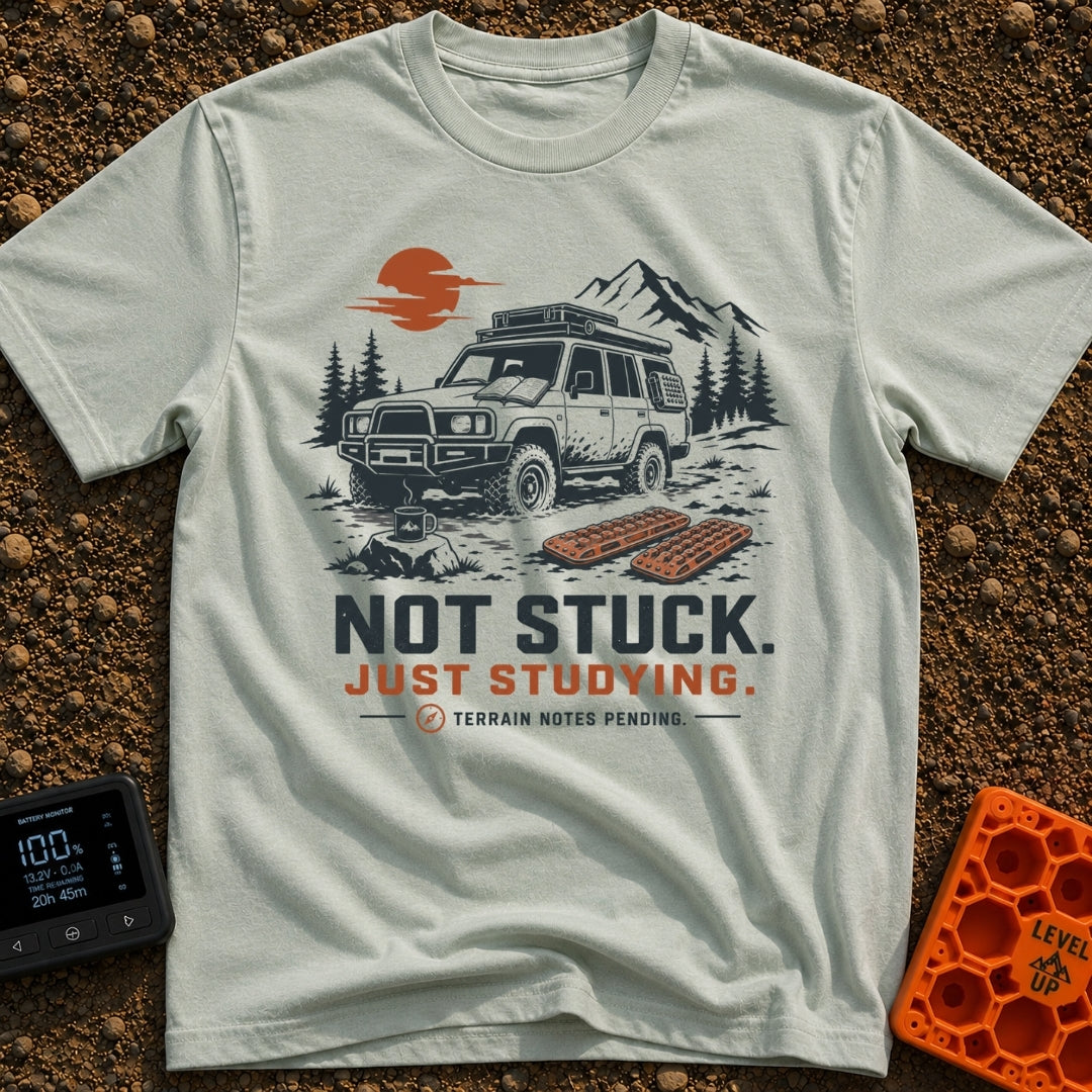 Not Stuck Just Studying - T-Shirt in Bay - An illustration of a muddy 4x4 SUV stopped on a rugged trail, with an open...