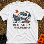 Not Stuck Just Studying - T-Shirt in White - An illustration of a muddy 4x4 SUV stopped on a rugged trail, with an open...