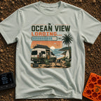 Ocean View Loading - T-Shirt in Bay - A camper van is parked by the ocean at sunset with a roof-mounted solar panel and a...