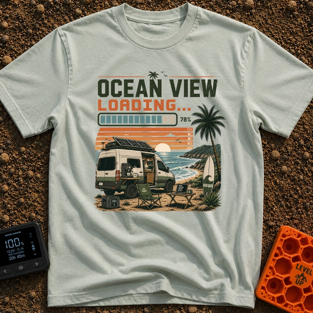 Ocean View Loading - T-Shirt in Bay - A camper van is parked by the ocean at sunset with a roof-mounted solar panel and a...