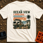 Ocean View Loading - T-Shirt in Ivory - A camper van is parked by the ocean at sunset with a roof-mounted solar panel and...