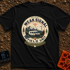 Weak Signal Field Unit - T-Shirt in Black - A round, badge-style illustration of a white camper van parked in a...