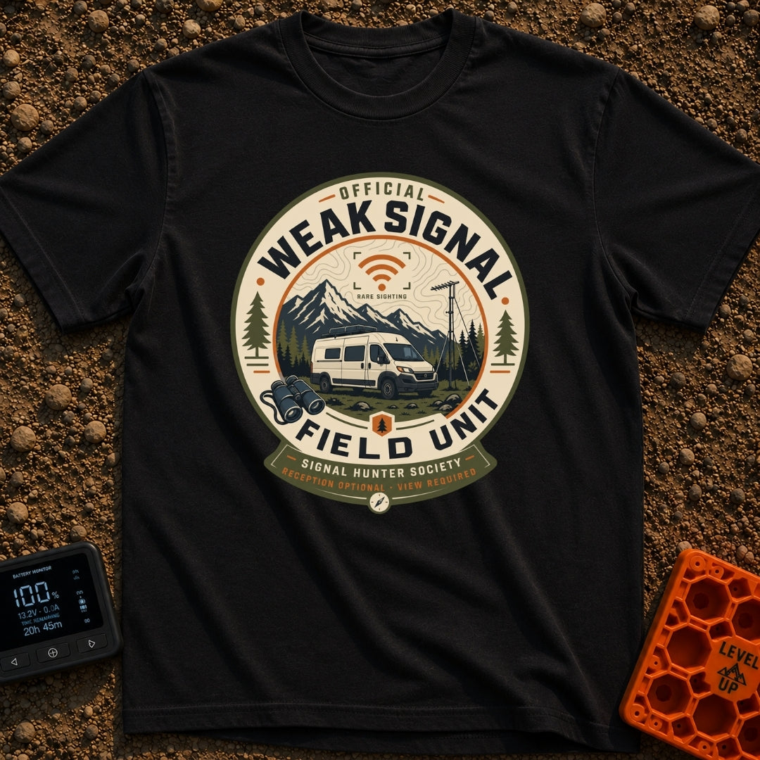 Weak Signal Field Unit - T-Shirt in Black - A round, badge-style illustration of a white camper van parked in a...
